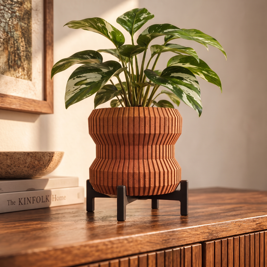 Waisted Fluted Planter in Burnt Rust holding a small pothos on a walnut console