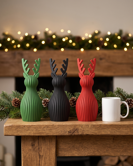 Three Ribbed Reindeer Sculptures in Mistletoe Green, Matte Black and Red on a wooden mantel with pine garland and warm lights
