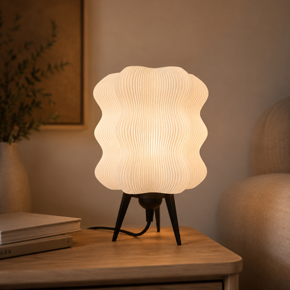 Wave Table Lamp in Matte White glowing on a wooden nightstand