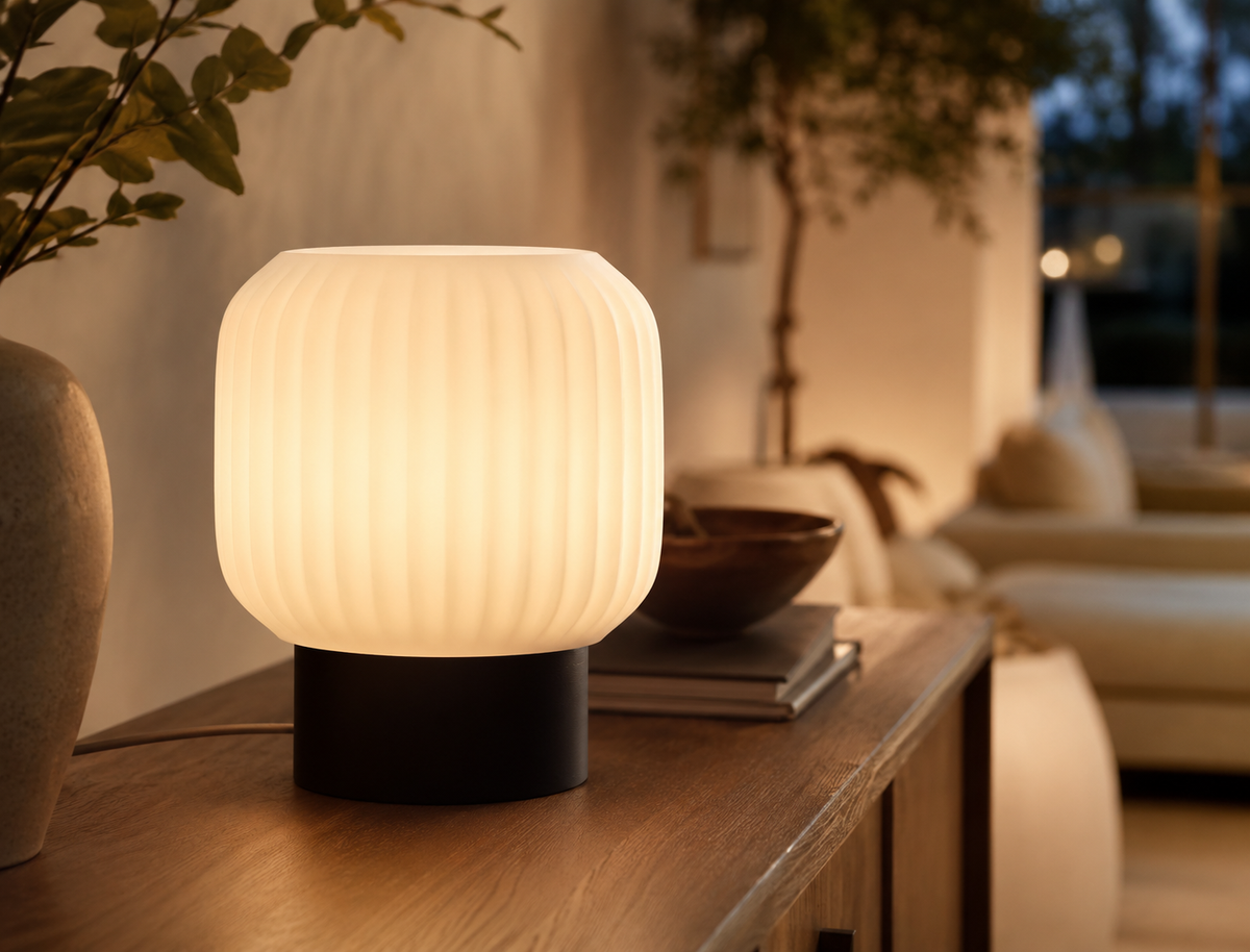 Drum Ribbed Table Lamp in Matte Black glowing on a wooden console table