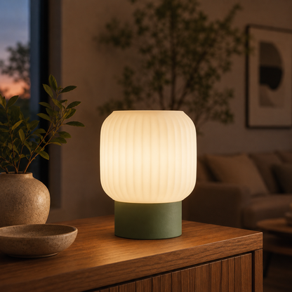 Drum Ribbed Table Lamp in Moss Green glowing on a wooden console table