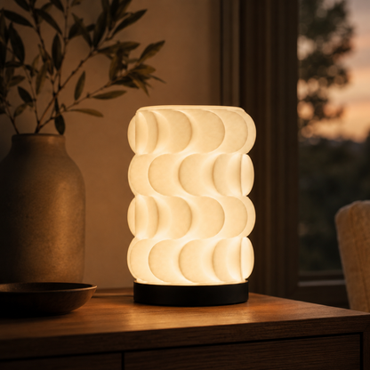 Scallop Table Lamp in Matte White glowing on a nightstand