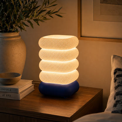 Stacked Bubble Table Lamp in Deep Indigo Blue glowing on a wooden console table