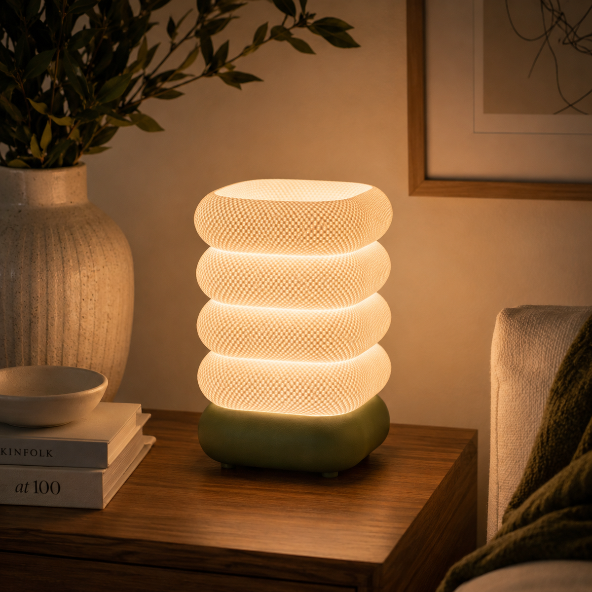 Stacked Bubble Table Lamp in Moss Green glowing on a wooden console table