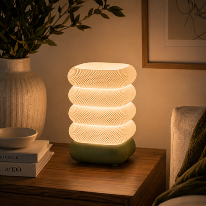 Stacked Bubble Table Lamp in Moss Green glowing on a wooden console table