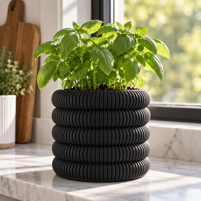 Coin Stack Planter in Matte Black holding a basil plant on a marble kitchen windowsill