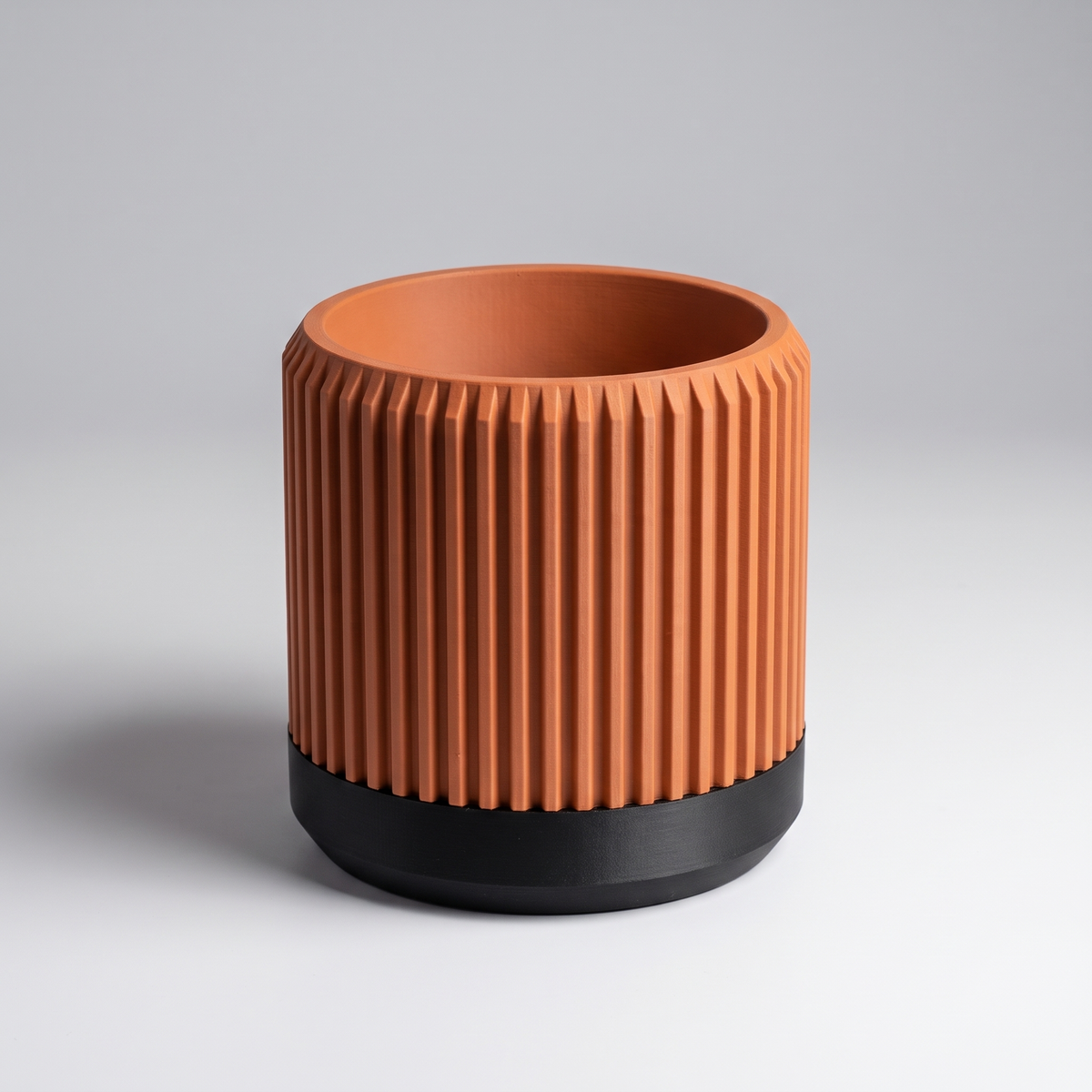 DiyArts Fluted Cylinder Planter with Saucer in Burnt Rust with matte black saucer, ribbed 4 inch plant pot, studio product shot