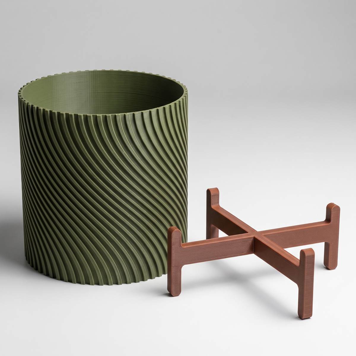Twisted Planter with Stand shown apart - spiral ribbed pot in Moss Green and the two-piece slotted cross stand in Burnt Rust