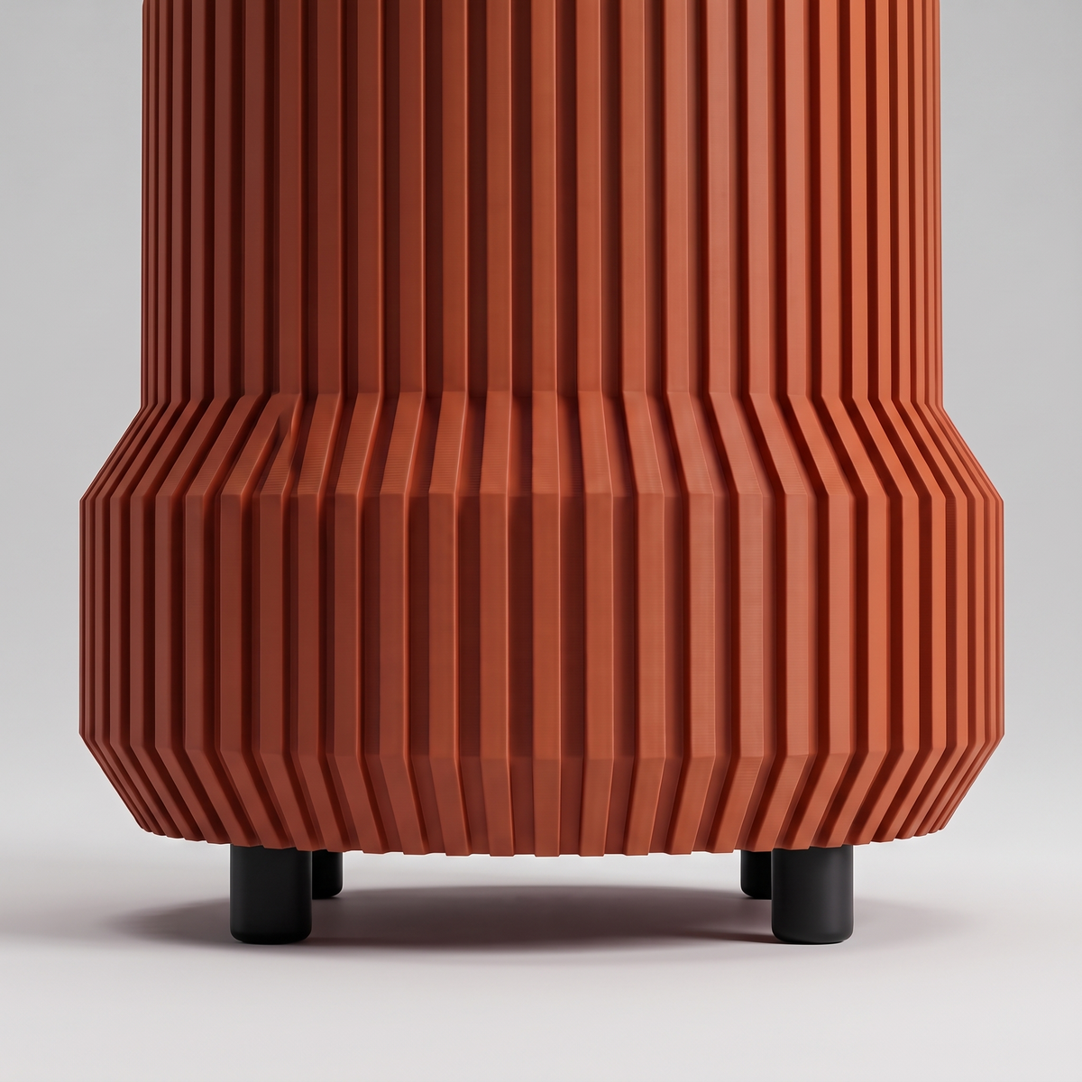 Chubby Fluted Planter in Burnt Rust seen from table level, showing the four short matte black feet under the fluted skirt