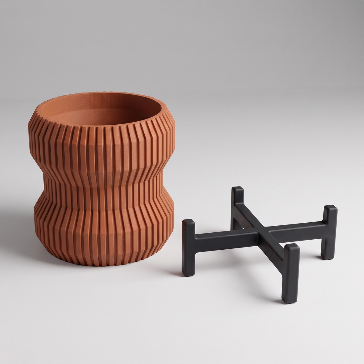 Waisted Fluted Planter shown apart - hourglass fluted pot in Burnt Rust and the matte black slotted cross stand with upturned tabs