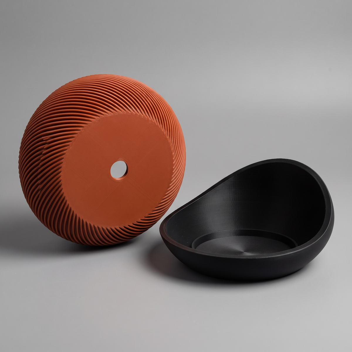Swirl Ribbed Bowl Planter shown as two pieces: the ribbed bowl tilted to show its drainage hole and the cradle saucer with its recess